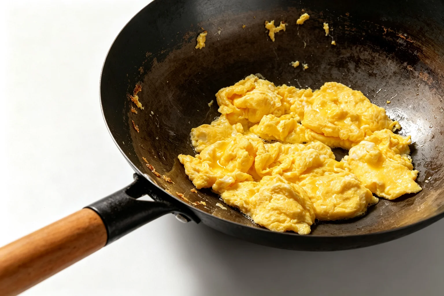 Large custardy egg curds with glossy center forming in a carbon steel wok showing the 80 percent cooked removal point for Chinese tomato egg stir fry