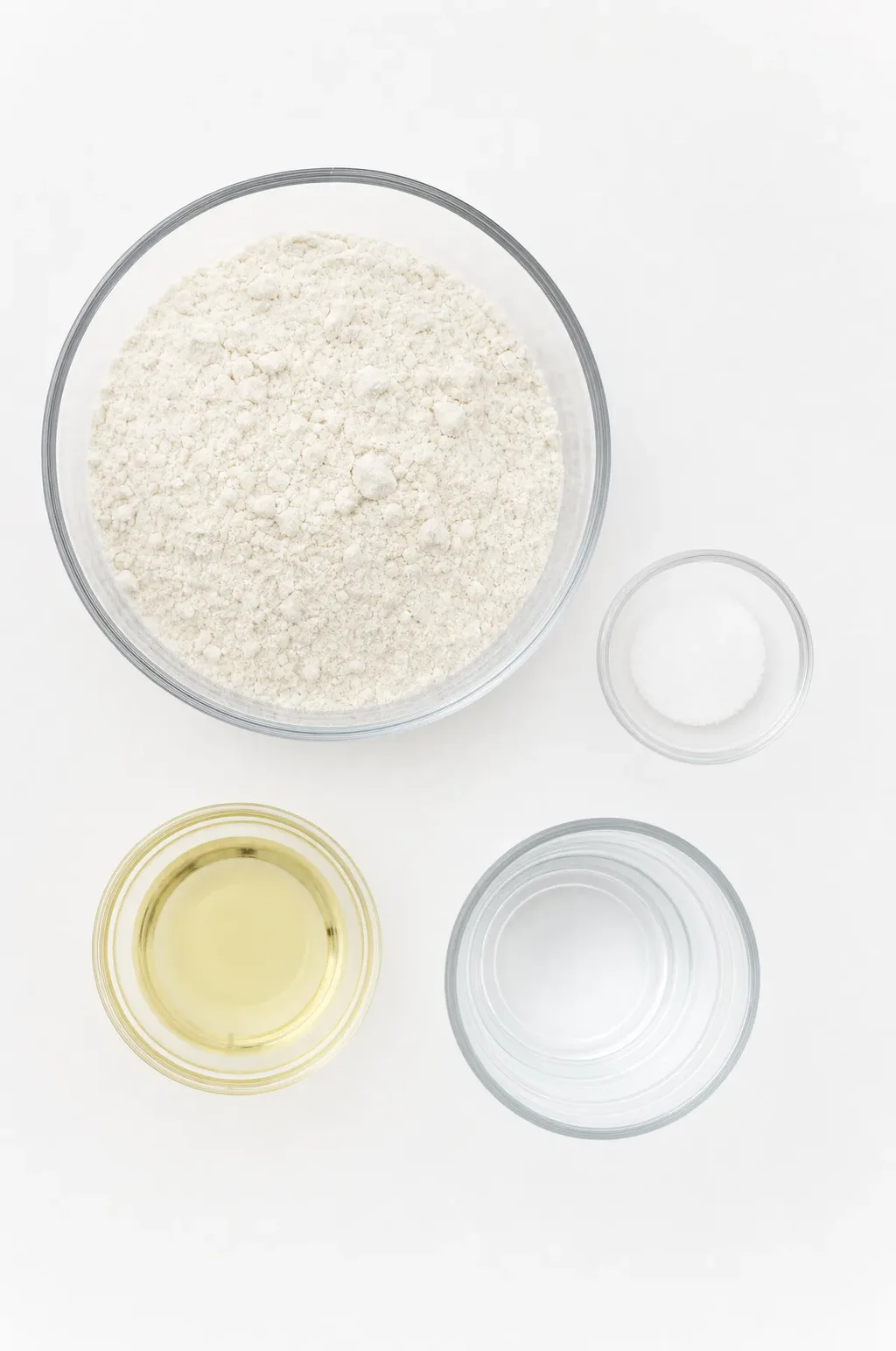Godamba roti ingredients laid flat — all-purpose flour, salt, coconut oil and water on a white surface